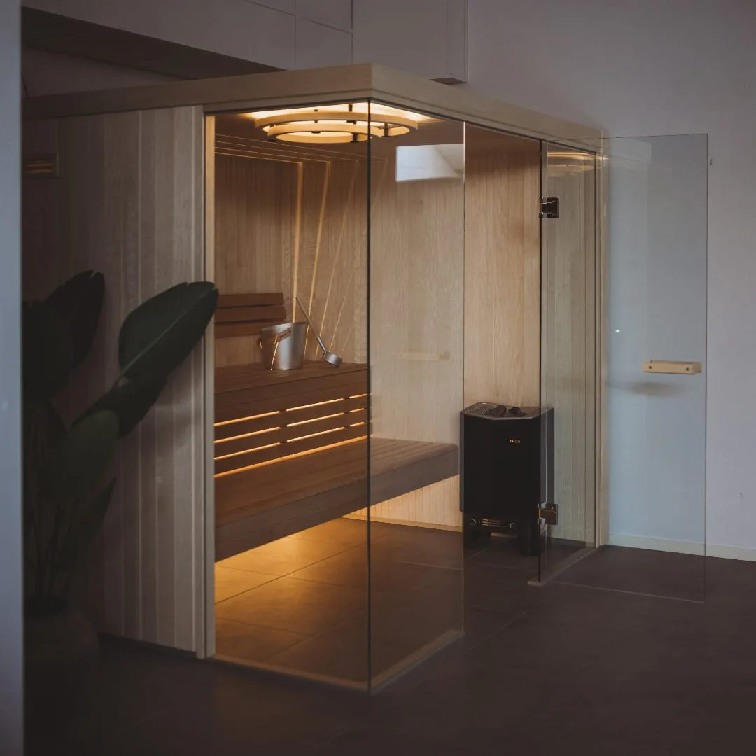 Tylö Custom Harmony indoor sauna with a frameless glass corner and integrated LED lighting, Roberts Leisure Isle of Man.