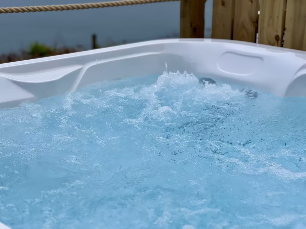 A close-up of crystal-clear, bubbling hot tub water, showcasing the powerful massage jets in action at a coastal installation on the Isle of Man.