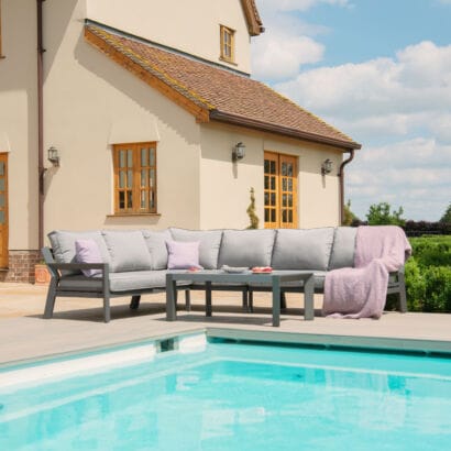 Maze New York Aluminium Corner Sofa Set in Dove Grey with matching coffee table on a wooden deck beside a swimming pool