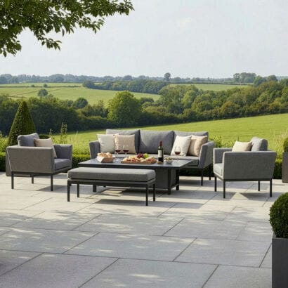 Luxury Pulse 3 seat all-weather outdoor fabric sofa and dining set in Zinc Grey with quick-dry cushions, styled on a stone patio overlooking the countryside.