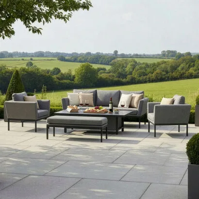 Luxury Pulse 3 seat all-weather outdoor fabric sofa and dining set in Zinc Grey with quick-dry cushions, styled on a stone patio overlooking the countryside.
