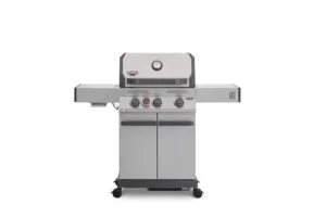 A direct front view of a stainless steel Primeliner S3 gas barbecue grill featuring a closed lid with an integrated temperature gauge, four control knobs, dual side shelves, and a two-door storage cabinet on wheels.
