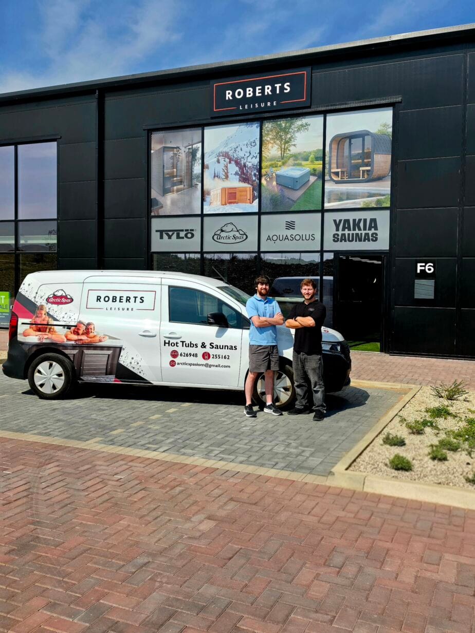 Exterior of the Roberts Leisure showroom on the Isle of Man, featuring two staff members next to a company van offering Arctic Spas, tylo Sauna, AquaSolos hot tubs and Yakia Saunas.