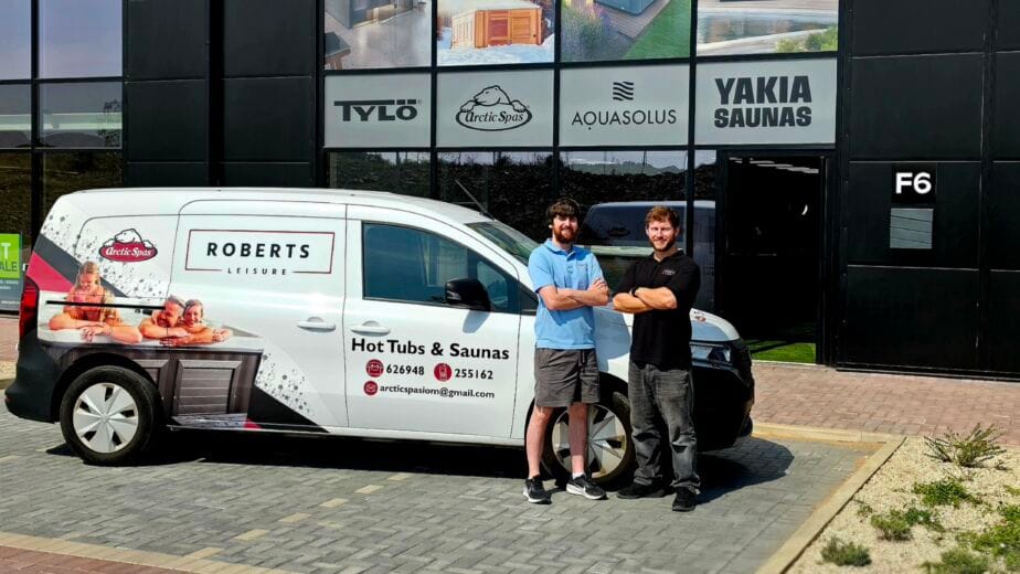 Exterior of the Roberts Leisure showroom on the Isle of Man, featuring two staff members next to a company van offering Arctic Spas, tylo Sauna, AquaSolos hot tubs and Yakia Saunas.