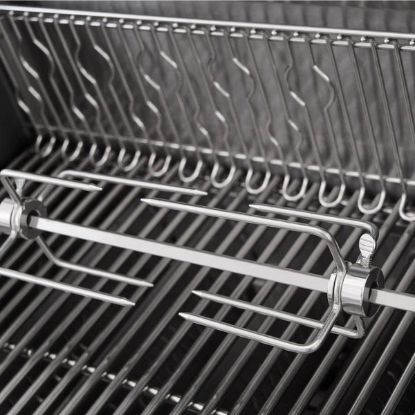 A close-up view of a stainless steel rotisserie spit rod with multi-prong meat forks mounted inside the Primeliner S4 gas barbecue over the cooking grates.