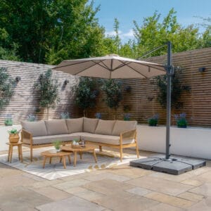 Fully opened Maze Helios 3m Round Rotating Cantilever Parasol in Clay Beige providing full shade coverage over outdoor seating on a stone patio, from Roberts Leisure, Isle of Man.