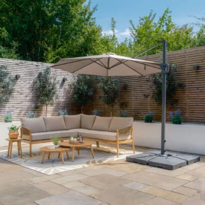 Fully opened Maze Helios 3m Round Rotating Cantilever Parasol in Clay Beige providing full shade coverage over outdoor seating on a stone patio, from Roberts Leisure, Isle of Man.