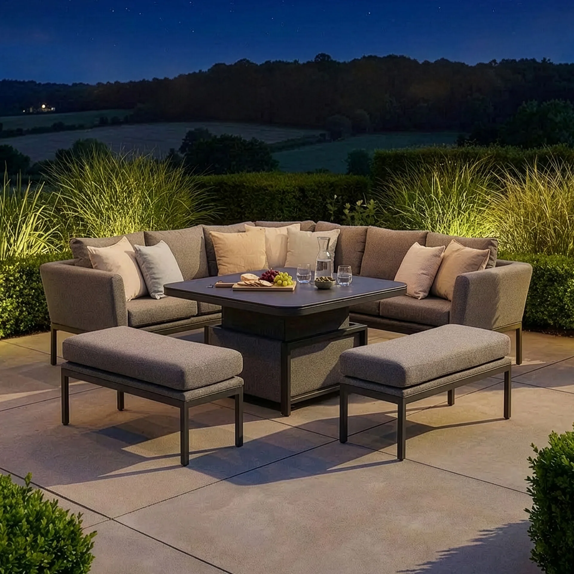 Evening patio view of the beautifully illuminated Maze - Outdoor Fabric Pulse Deluxe Square Corner Dining Set with Rising Table - Zinc Grey, available exclusively at Roberts Leisure, Isle of Man.