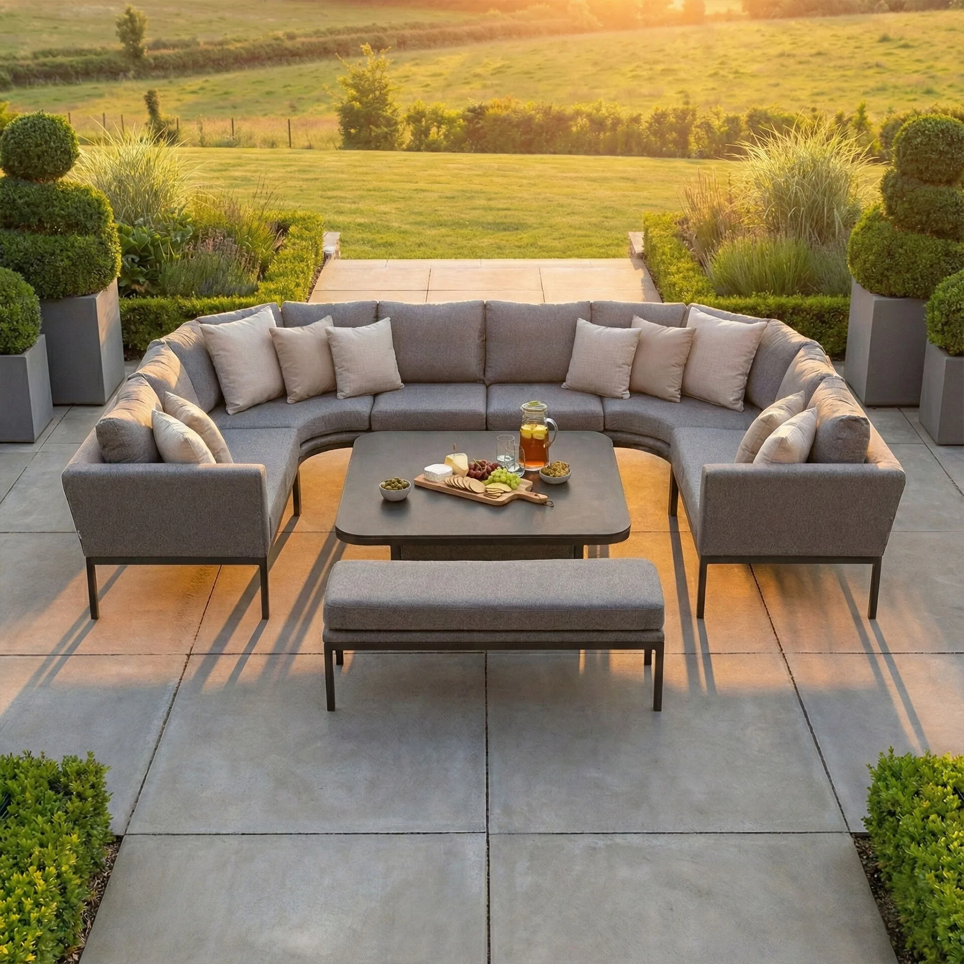Golden hour sunset view of the Maze - Outdoor Fabric Pulse U Shape Corner Dining Set with Rising Table - Zinc Grey configured for a relaxed coffee setting at Roberts Leisure, Isle of Man.