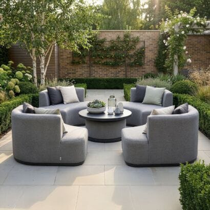 The Outdoor Fabric Snug Lifestyle Suite with Rising Table - Zinc Grey configured as 4 separate chairs around a lowered coffee table on a patio at Roberts Leisure, Isle of Man.
