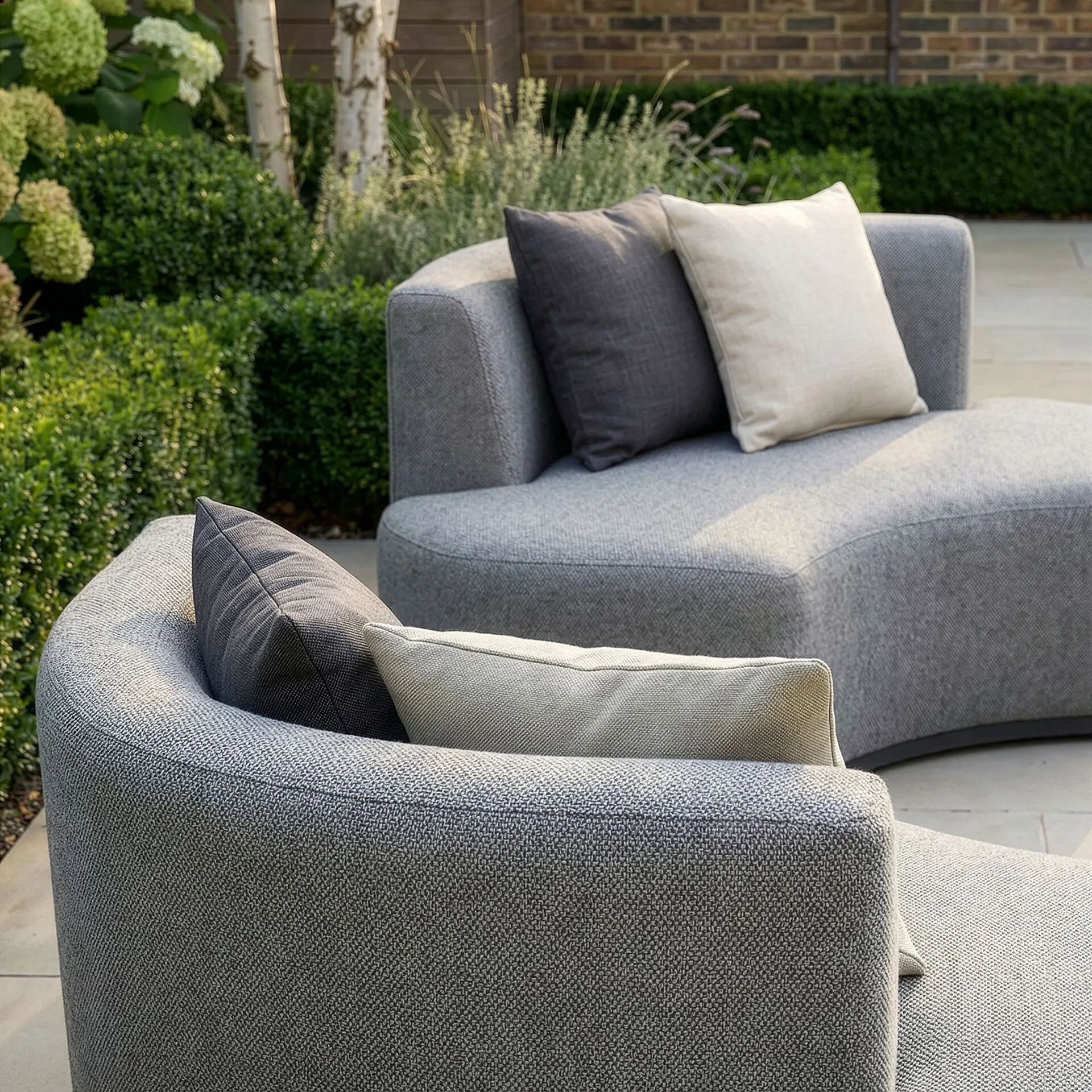 Detail shot highlighting the solution-dyed acrylic fabric and cushions of the Outdoor Fabric Snug Lifestyle Suite with Rising Table - Zinc Grey at Roberts Leisure, Isle of Man.