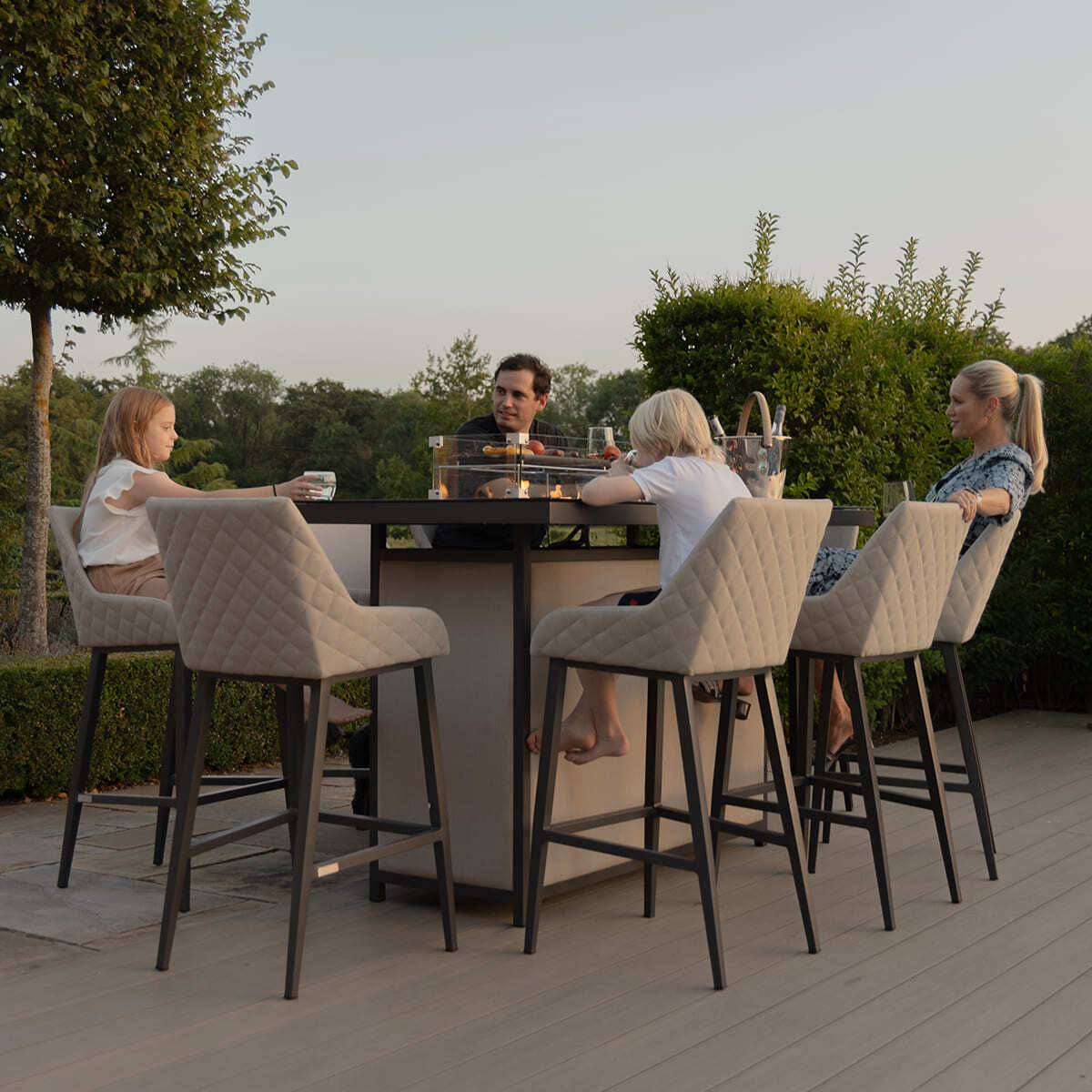A family enjoying a casual evening around the Maze - Outdoor Fabric Regal 8 Seat Rectangular Bar Set Latte with café frame poolside at Roberts Leisure, Isle of Man.
