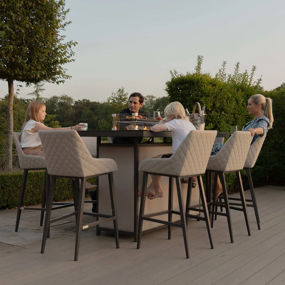 A family enjoying a casual evening around the Maze - Outdoor Fabric Regal 8 Seat Rectangular Bar Set Latte with café frame poolside at Roberts Leisure, Isle of Man.